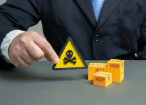 A person in a suit holds a triangular yellow warning sign with a skull and crossbones near yellow blocks labeled "tax." The tone is cautionary and serious.