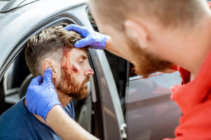 Paramedic treating a driver with a head injury after a car accident.